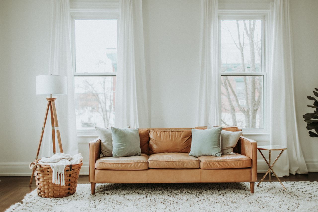 about-us A cozy minimalist living room with a leather sofa and stylish decor.
